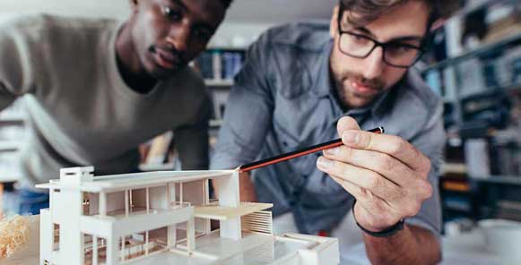 House plans - Two designers reviewing a scale model of a home | Monster House Plans